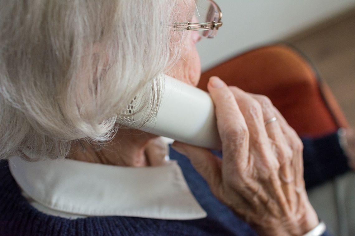 An elderly woman talks on the phone.