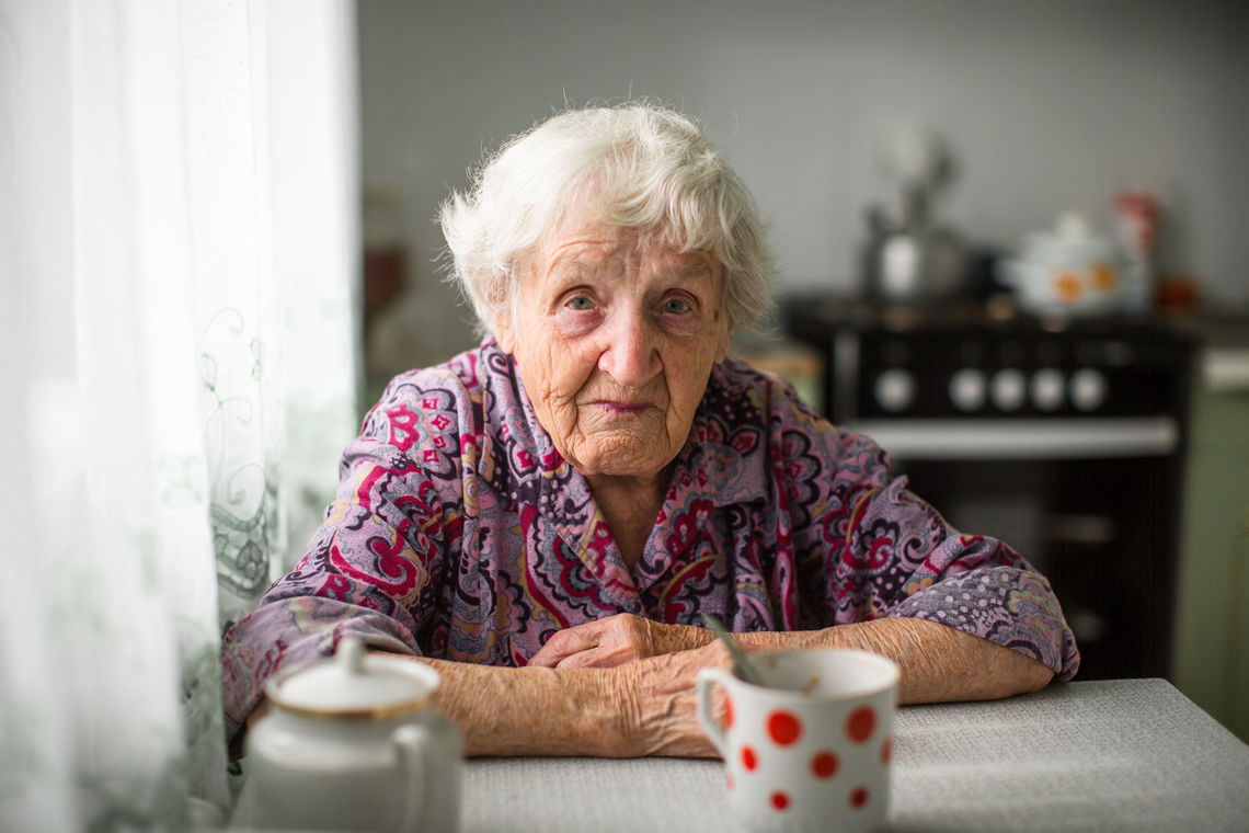 An elderly woman sitting at the kitchen table.