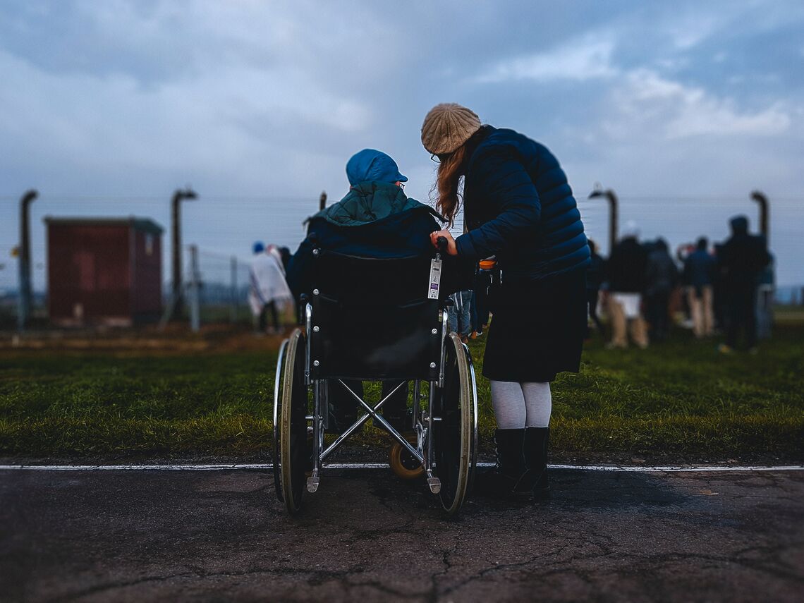 A woman stands and talks to a person in a wheelchair